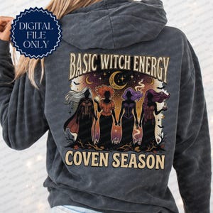 Puede incluir: Una sudadera con capucha gris carbón que presenta un gráfico en la espalda con el texto "BASIC WITCH ENERGY" y "COVEN SEASON". El diseño muestra cuatro figuras silueteadas con vestidos largos sobre un cielo nocturno con luna creciente, estrellas y murciélagos.