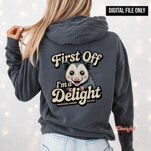 May include: Dark gray hoodie with a graphic of an opossum and the text "First Off I'm a Delight emotionally unstable but cute." The hoodie is a digital file.