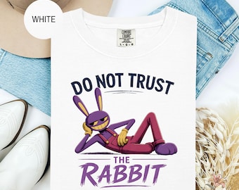May include: White crew neck t-shirt with a graphic of a purple rabbit in overalls, with the text "DO NOT TRUST THE RABBIT". The rabbit is smiling and reclining. The shirt is on a denim background.