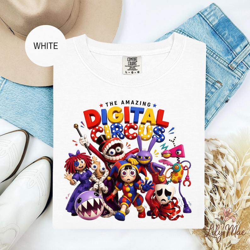 K&ouml;nnte beinhalten: Wei&szlig;es T-Shirt mit Rundhalsausschnitt und einem farbenfrohen Grafikdesign von Zeichentrickfiguren und dem Text "THE AMAZING DIGITAL CIRCUS". Das Design zeigt skurrile Figuren in leuchtenden Farben, ideal f&uuml;r Fans von Zeichentrickfilmen.