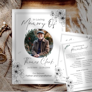 Puede incluir: Una tarjeta conmemorativa con el texto "In Loving Memory Of Thomas Clark" y una foto de un hombre. La tarjeta está decorada con arte lineal floral e incluye fechas y las palabras "Our Beloved Father and Grandfather."
