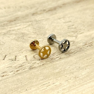 May include: Two star-shaped stud earrings. One is gold-colored, the other is silver-colored. Each earring has a flat, round backing and a post. The star design is in the center of the earring.