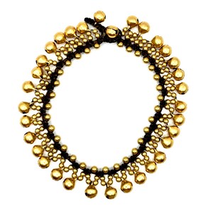 K&ouml;nnte beinhalten: Ein kreisf&ouml;rmiges Fu&szlig;kettchen mit einer Basis aus dunkelbrauner Kordel, die mit zahlreichen kleinen, metallisch goldfarbenen, kugelf&ouml;rmigen Gl&ouml;ckchen verziert ist. Die Gl&ouml;ckchen sind in einem sich wiederholenden Muster entlang der Kordel angeordnet.