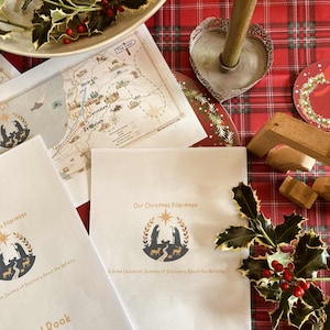 Può includere: Una scena natalizia festosa con una tovaglia a quadri rossa, una candela accesa, piatti decorativi e agrifoglio. Diverse pagine stampate mostrano una mappa e il testo "Our Christmas Pilgrimage" e "Carol Book".