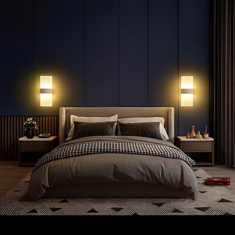 K&ouml;nnte beinhalten: Ein modernes Schlafzimmer mit einem gro&szlig;en Bett, zwei Nachttischen und zwei Wandleuchten. Das Bett hat eine graue Bettdecke und eine schwarz-wei&szlig; gemusterte Decke. Die W&auml;nde sind dunkelblau, und die Wandleuchten strahlen ein warmes, einladendes Licht aus. Der Raum ist mit einem Teppich und Vorh&auml;ngen dekoriert.