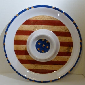 May include: A white serving platter with a red, white, and blue American flag design. The platter has a smaller, removable bowl in the center.