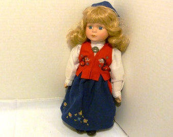 Preciosa muñeca étnica noruega con traje tradicional Bunad: chaleco rojo bordado en lana y falda larga azul.