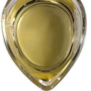 Op de afbeelding: Een heldere, hartvormige beker gevuld met een gele vloeistof. De vloeistof heeft een lichte schuimlaag aan de zijkant. De tekst onderaan luidt "AS 40 Surfactant Alpha Olefin Sulfonate AOS".