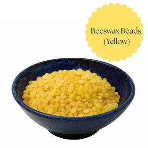 Könnte beinhalten: Eine dunkelblaue Keramikschale gefüllt mit gelben Bienenwachsperlen. Die Perlen sind klein, rund und gleichmäßig groß. Ein gelber, gezackter Kreis mit dem Text "Beeswax Beads (Yellow)" befindet sich in der oberen rechten Ecke.