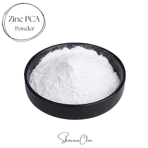 May include: A small black bowl filled with fine white Zinc PCA Powder. The text Zinc PCA Powder is enclosed in a circular line at the top left, and the text Skincare Clue is written in a cursive script at the bottom center of the image.
