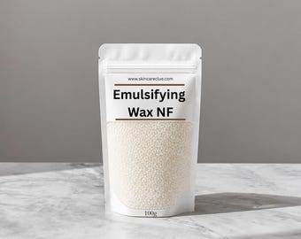 May include: A white stand-up pouch containing small, off-white wax beads. The label features the text www.skincareclue.com, Emulsifying Wax NF, and 100g. The packaging is opaque at the top and bottom with a clear window showing the contents.