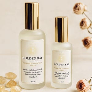 Può includere: Due flaconi spray in vetro con tappi dorati sono etichettati "GOLDEN RAY VIERATION ELEVATION SPRAY". I flaconi sono da 100 ml e 40 ml. Il testo sull'etichetta recita: "La luce dorata scorre attraverso di me, elevando la mia vibrazione alla frequenza della gioia e dell'abbondanza."