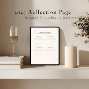 Op de afbeelding: Een digitale reflectiepagina voor 2025, ontworpen voor een rustiger, helderder jaar. De pagina wordt weergegeven op een zwarte tablet, met prompts voor zelfreflectie. Een glas wijn, een stapel boeken en een kaars staan ook op de plank.