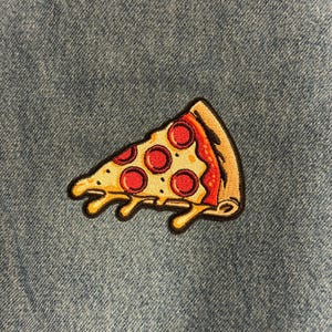 May include: Embroidered pizza slice patch with pepperoni toppings, yellow cheese, and a brown crust. The patch is set against a blue denim background. This patch is perfect for adding to a jacket, backpack, or other fabric items.