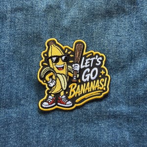 May include: An embroidered patch featuring a yellow banana character wearing black sunglasses and red and white sneakers. The character holds a brown baseball bat. The text LET'S GO BANANAS! is stitched in white on a black background with a yellow border.