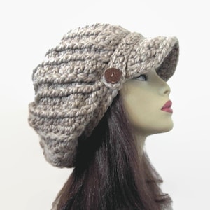May include: A beige crocheted slouchy hat with a wide brim and a brown button.
