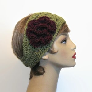 May include: A green crocheted headband with a large, dark red flower accent. The headband is wide and covers the forehead, with the flower positioned on the side. The handmade accessory is suitable for various occasions.