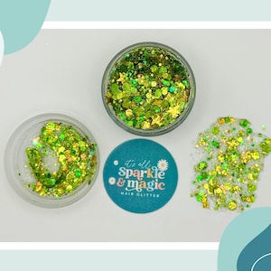May include: Overhead shot of three containers of green glitter. Two clear jars hold glitter, one open, the other closed. A small teal circle with the text "it's all Sparkle & magic HAIR GLITTER" is also visible.