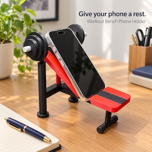 May include: A workout bench phone holder featuring a black and red design with barbell weight plates on the sides. The stand holds a smartphone at an angle. Text on the image reads: Give your phone a rest. Workout Bench Phone Holder.