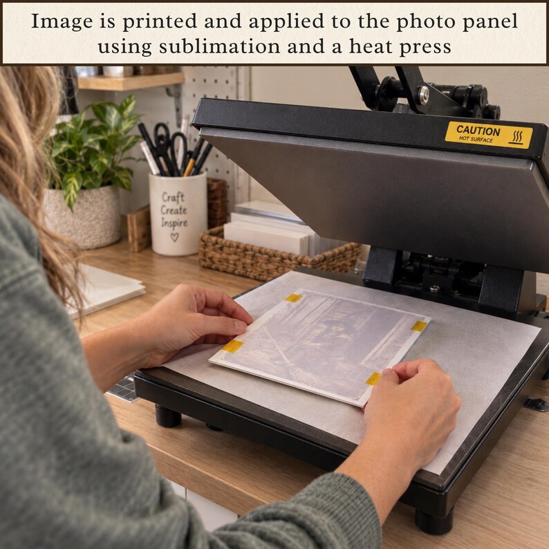May include: A black heat press machine with a yellow caution label is used to apply a printed image onto a photo panel. The text at the top states: Image is printed and applied to the photo panel using sublimation and a heat press.