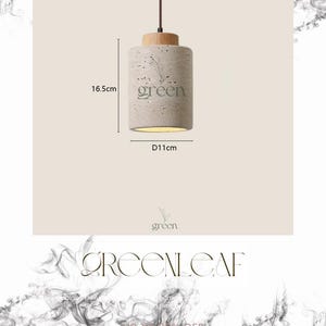 May include: A cylindrical pendant light with a light gray concrete body and a wooden top. The light fixture is 6.5 inches tall and 4.3 inches in diameter. The word "green" is printed on the front. A brown cord suspends the light.
