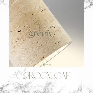 May include: Close-up of a cylindrical object made of beige stone with a textured surface. The word "green" is printed in a light green color on the stone. The object is lit from within, creating a soft glow.