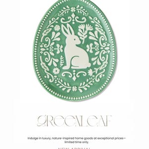 May include: Green ceramic Easter egg-shaped decorative plate with a white rabbit and floral design. The plate has a dotted border and the text "GREENLEAF" and "NEW ARRIVAL". A nature-inspired home goods item.