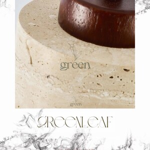 May include: Close-up of a beige stone lamp base with a dark brown wooden top. The word "green" is printed in a light green color on the lamp base. The text "GREENLEAF" is printed in a dark green color.