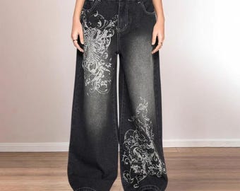 May include: Black wide-leg jeans with a faded wash and decorative white floral patterns on the front. The jeans have a high waist and are paired with black platform shoes. The overall style is reminiscent of the early 2000s.