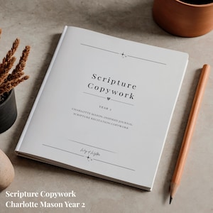 May include: A white softcover book titled Scripture Copywork Year 2, featuring black text and minimalist line graphics on the front cover. The book includes the subtitle Charlotte Mason-Inspired Journal Scripture Recitation Copywork.