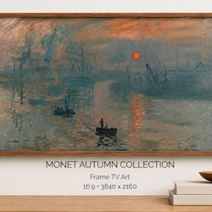 Op de afbeelding: Een ingelijste print van een waterlandschap schilderij met een zonsondergang. Het kunstwerk toont een rode zon, boten en een weerspiegeling op het water. De tekst "MONET AUTUMN COLLECTION" staat eronder.