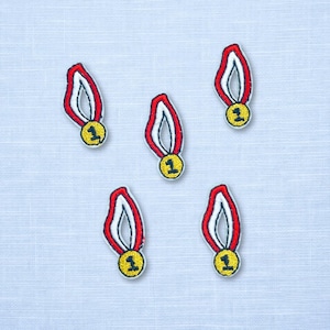 May include: Five embroidered patches, each shaped like a gold medal with a red and white ribbon. The circular medal features the number one in black thread. The patches are arranged in a scattered pattern against a light blue textured background.
