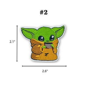 May include: Embroidered patch featuring a green alien character with large ears and black eyes, wearing a tan robe. The patch is 2.1 inches tall and 2.6 inches wide, with the number "#2" above the character.