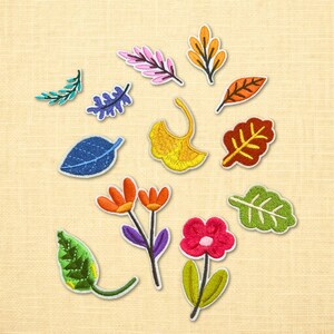 May include: A collection of embroidered patches featuring various leaf and flower designs. The patches include a blue leaf, orange flowers, and a red flower. The patches are in various colors, including green, orange, pink, and yellow.