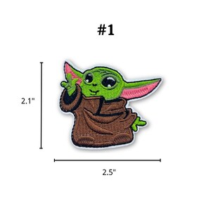 May include: Embroidered patch featuring a green character with large eyes and pointed ears, wearing a brown robe. The patch is 2.5 inches wide and 2.1 inches tall, with the text "#1" above the character.