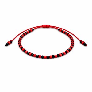 May include: Red and black beaded bracelet. The bracelet features small, round beads in alternating red and black colors. The adjustable cord is red, with a sliding knot closure. The ends of the bracelet have small black beads.