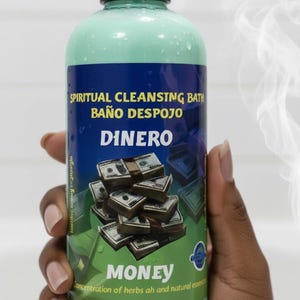 May include: A green and blue bottle labelled "Spiritual Cleansing Bath" with the word "Dinero" and "Money" in large text. The label features illustrations of stacks of money. Steam rises from the bottle.