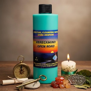 Puede incluir: Una botella turquesa con tapa negra, etiquetada como "SPIRITUAL CLEANSING BATHS BAÑO DESPOJO ABRECAMINO OPEN ROAD". Una vela encendida, una brújula, una llave y otros objetos están sobre una superficie de madera. La botella contiene 237 ml.