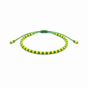 May include: Adjustable bracelet featuring alternating yellow and green beads strung on a green cord. The bracelet has a sliding knot closure for a customizable fit. The beads are small and evenly spaced, creating a simple, yet stylish accessory.