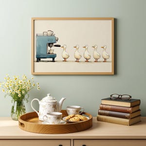 Könnte beinhalten: Ein gerahmter Kunstdruck mit einer blauen Espressomaschine und einer Reihe von fünf weißen Enten. Der Druck hängt über einem Holztablett mit einer weißen, floral verzierten Teekanne, zwei passenden Teetassen und einem Teller mit Keksen.