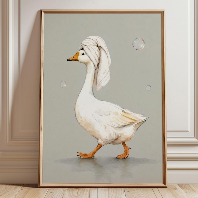 May include: Watercolor print of a white goose wearing a white towel on its head, walking on a gray surface. The goose has an orange beak and feet. The background is a light gray with two bubbles. The artwork is framed in a wooden frame.