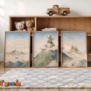 May include: Three framed art prints with watercolour illustrations of dragons in a mountain landscape. One print shows a rainbow, another a dragon on a cloud, and the third a sleeping dragon. The frames are light brown.