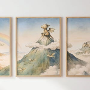 May include: A set of three framed art prints with dragon illustrations. One print depicts a dragon on a mountain, others show dragons flying and a rainbow. The artwork uses a soft colour palette, creating a dreamy, fairytale aesthetic.