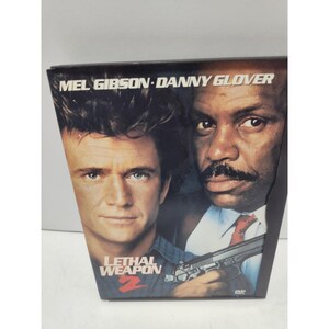 May include: A DVD case for the film Lethal Weapon 2 featuring the faces of Mel Gibson and Danny Glover. The title Lethal Weapon 2 is printed in red and white text at the bottom, and a black handgun is visible in the lower right corner.