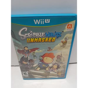 May include: A blue Wii U video game case for Scribblenauts Unmasked: A DC Comics Adventure. The cover features cartoon-style illustrations of DC characters including Superman, Batman, and Wonder Woman alongside the main character Maxwell.