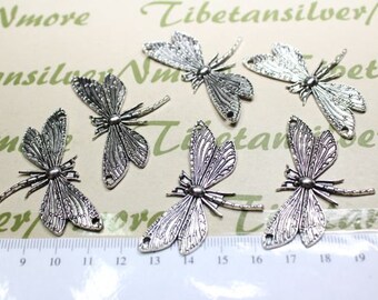 Könnte beinhalten: Sieben silberne Libellen-Anhänger mit filigranen Details. Die Anhänger sind etwa 5 cm lang und haben zwei Löcher zum Anbringen an Schmuck oder andere Bastelarbeiten.