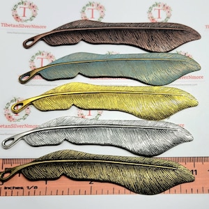 May include: Five metal feather bookmarks in different colors: copper, blue-green, gold, silver, and brass. The bookmarks are arranged in a row, with the copper bookmark at the top and the brass bookmark at the bottom. The bookmarks are all about 5 inches long.