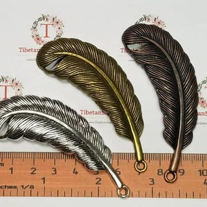 May include: Three metal feather charms in silver, gold, and copper tones. Each charm has a loop at the bottom for attaching to jewelry or other crafts.