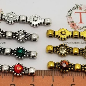 May include: Six silver and gold connector charms with clear, red, and green rhinestones. The charms are approximately 2.5 cm long and feature a decorative design.