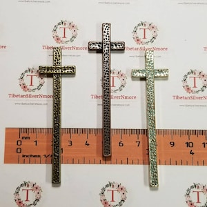 May include: Three metal cross charms in different finishes: antique gold, silver, and antique green. Each cross is about 2 inches tall and has a hammered texture.